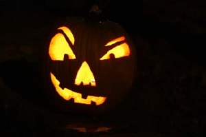 A carved pumpkin in the dark with a candle lighting up the face